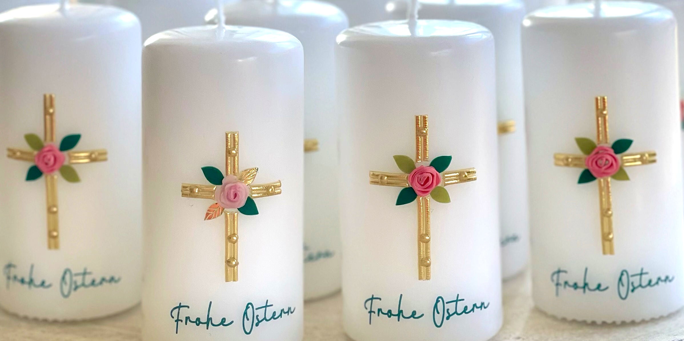 Osterkerzen mit goldenen Kreuzen und Rosenblüten
