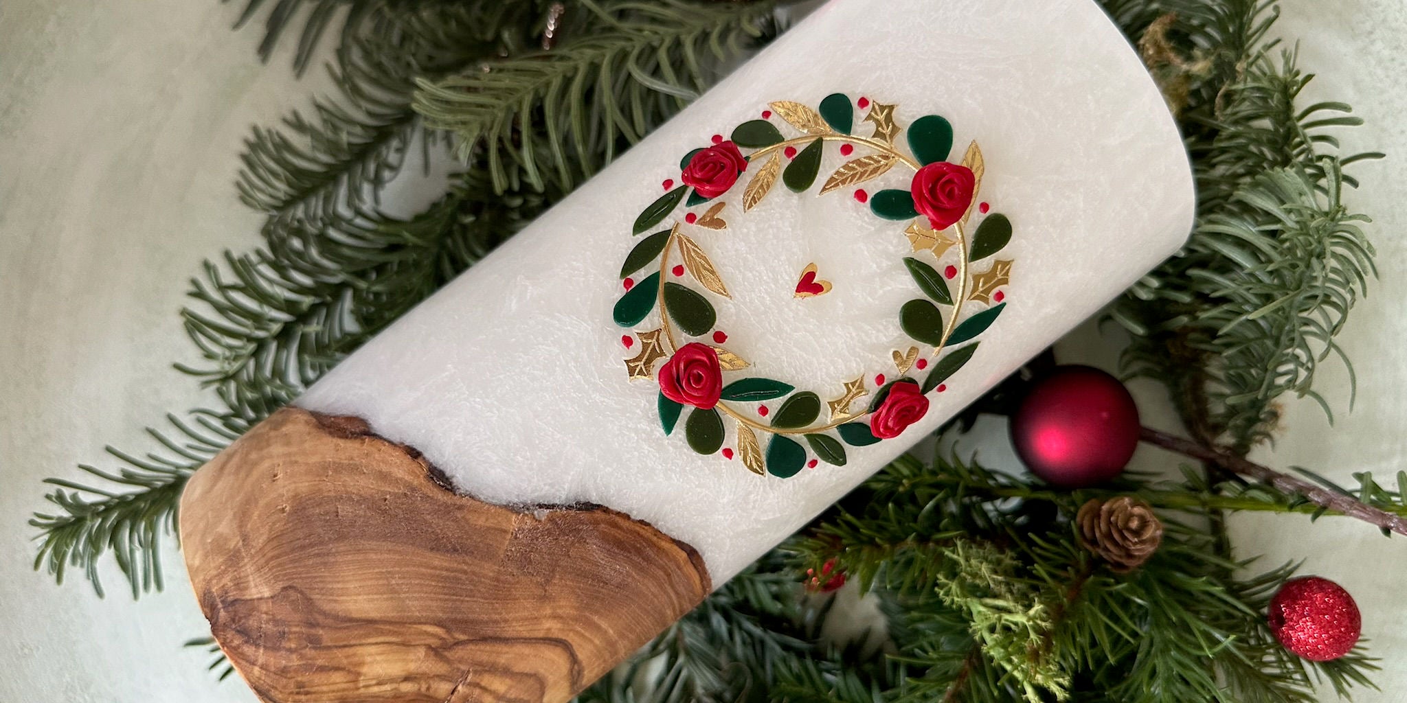 Weihnachtskerze mit Holzelement Dekoriert auf Tannenzweigen und Roten Christbaumkugeln