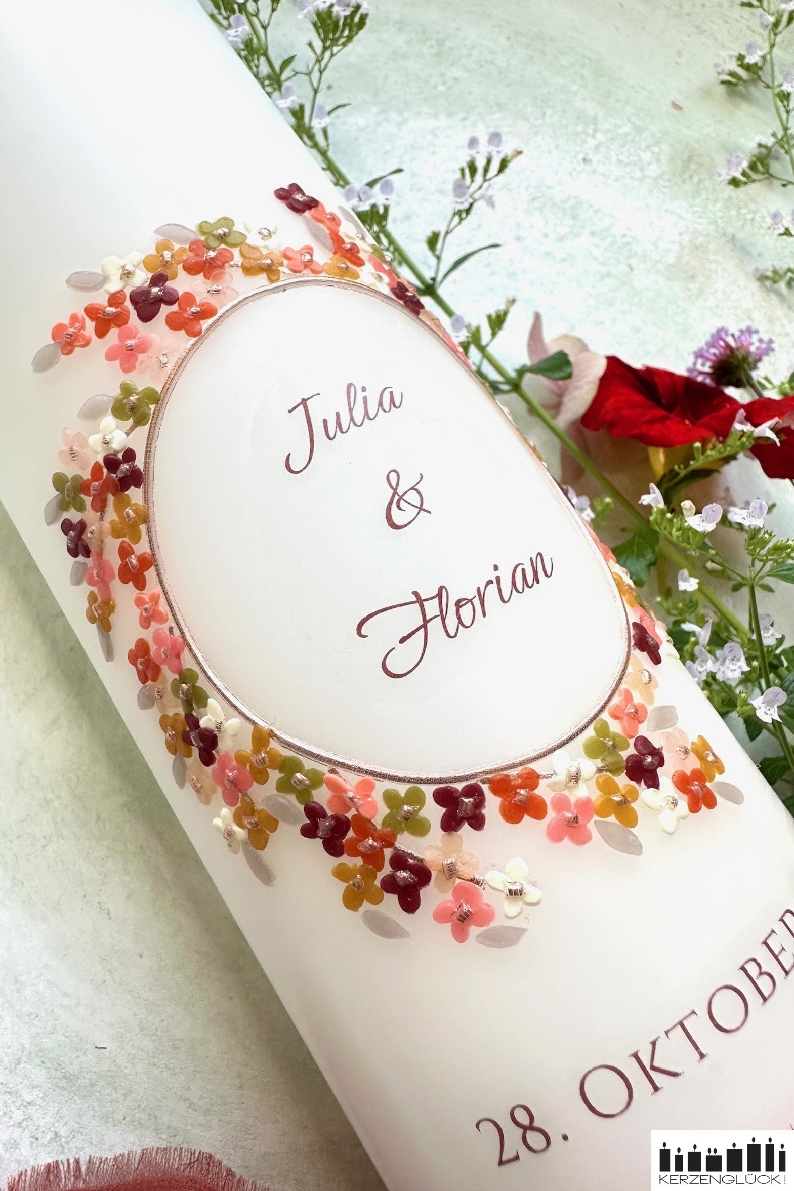 Detailaufnahme von Hochzeitskerze in Herbstfarben mit bunten Blumen dekoriert