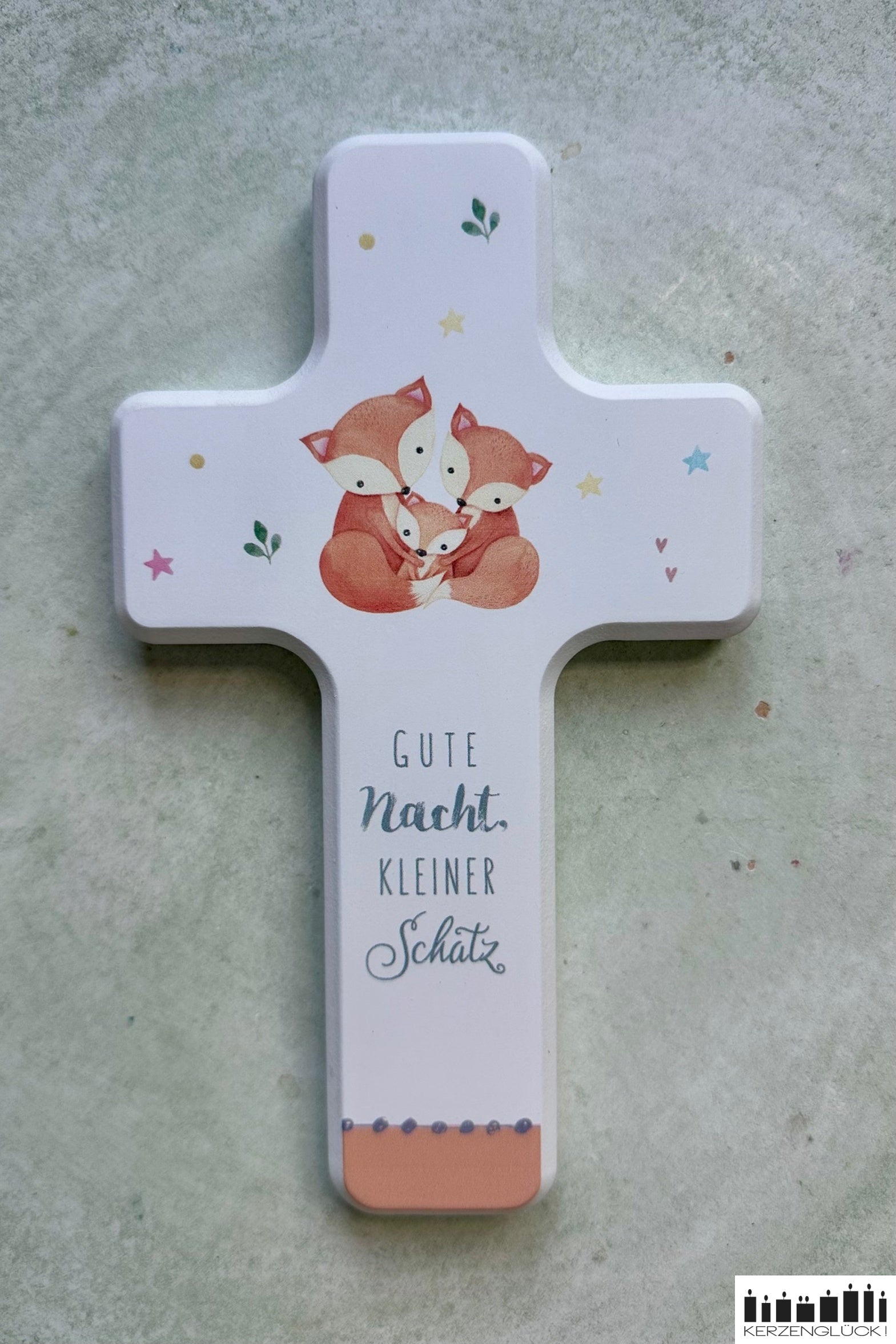 Weißes Holzkreuz mit Fuchsfamilie auf hellem Teller