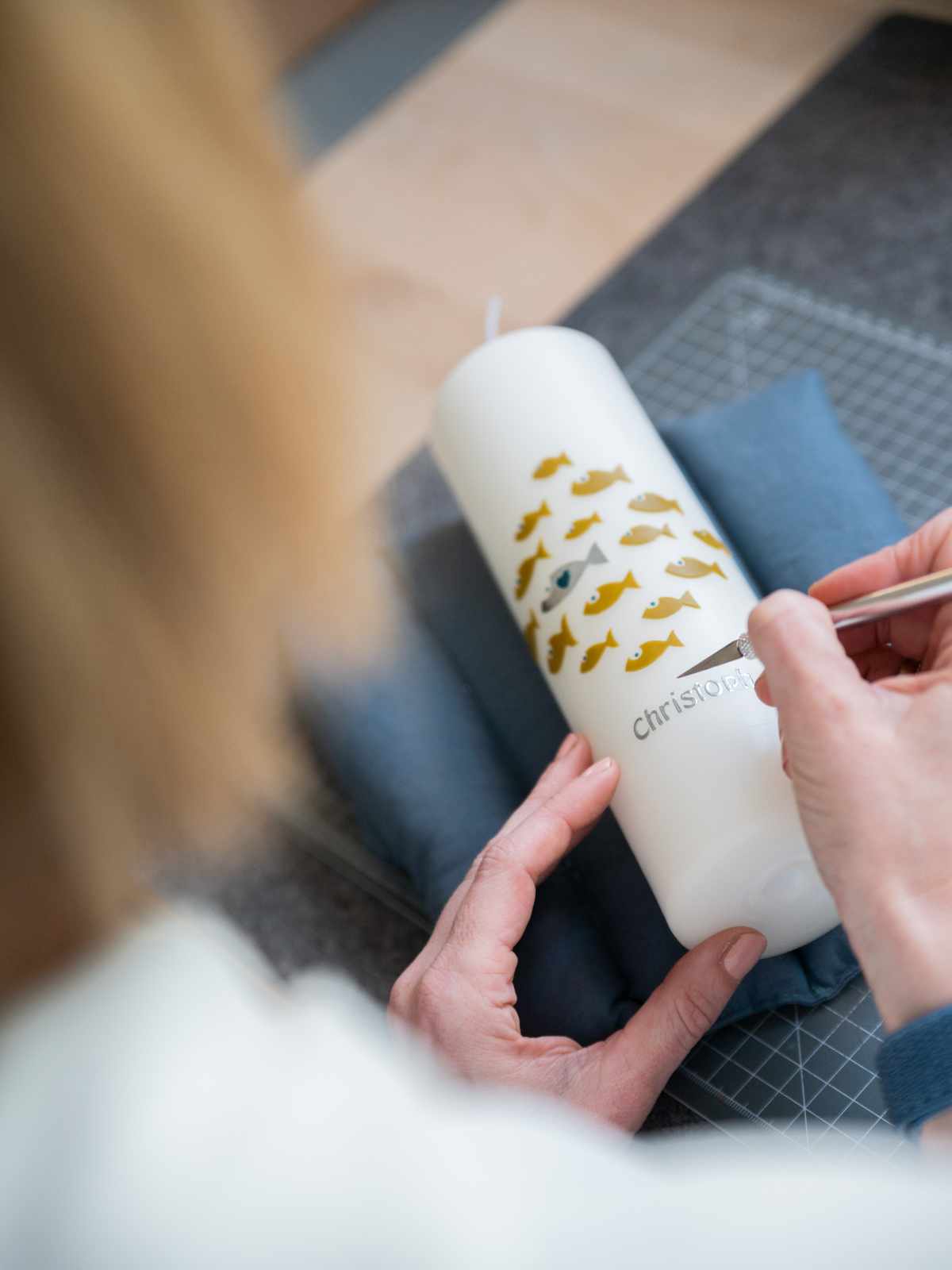 Verzierung einer Taufkerze mit Wachs. Kleine Fische aus Wachs