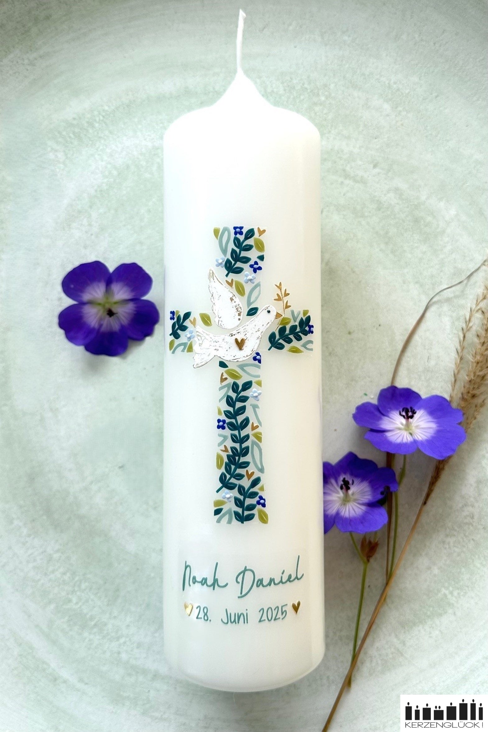 Taufkerze Blütenkreuz mit Gräsern und blauen Blüten dekoriert