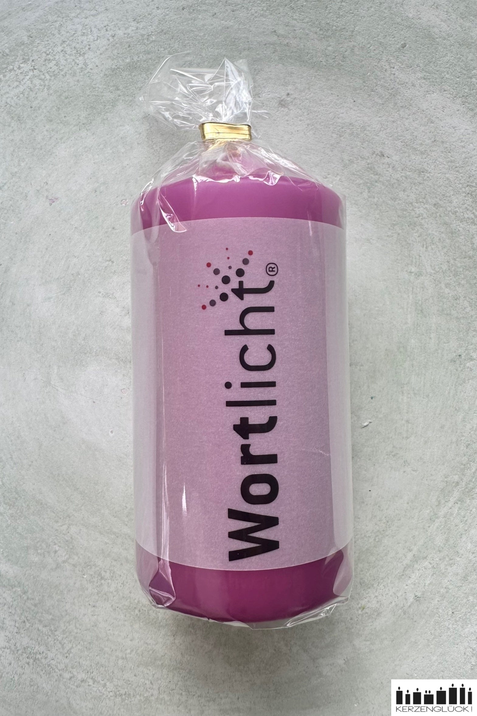 Kerze in Cellophanhülle und Pergamentbanderole mit Aufschrift "Wortlicht", violette Kerze