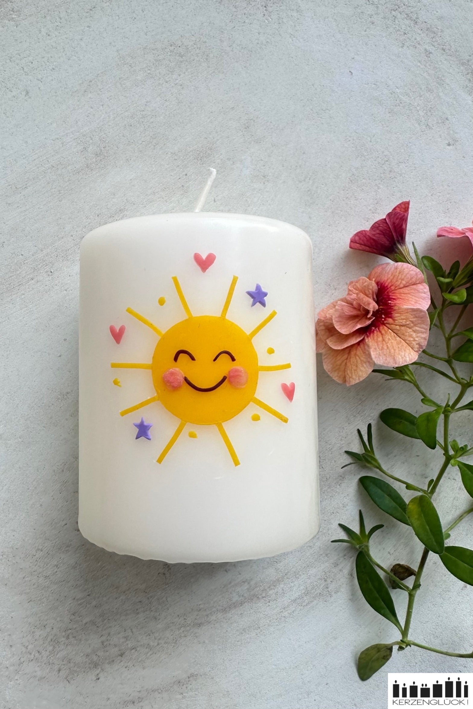 Gastgeschenkkerze auf hellem Untergrund mit Blüte dekoriert