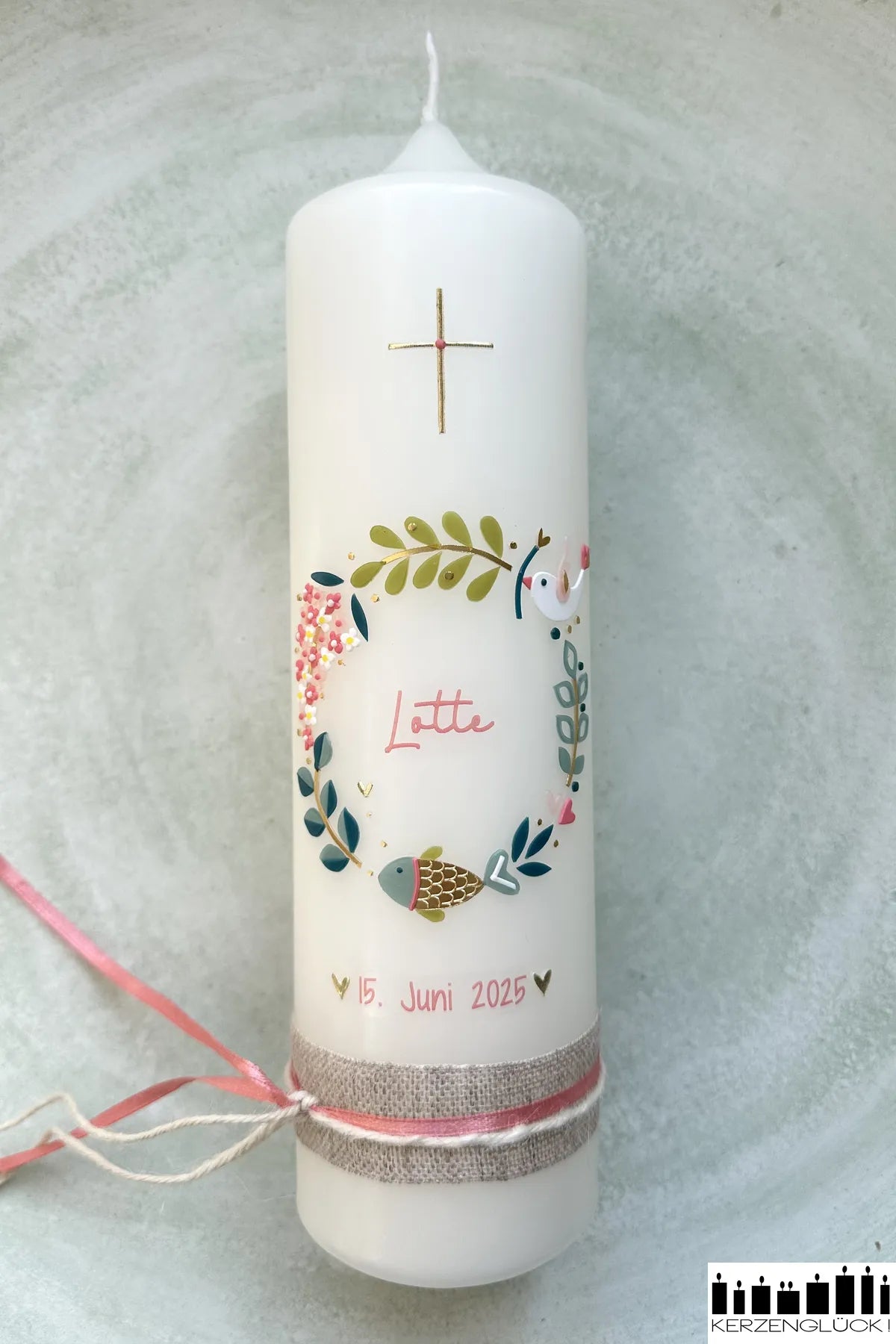 Taufkerze Kranz mit Symbolen liegend in einer hellen Schale